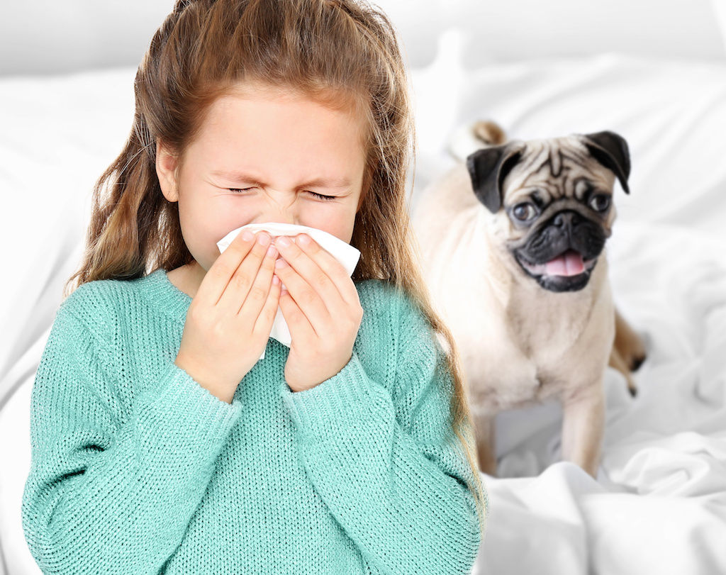 Girl sneezing with dog next to her